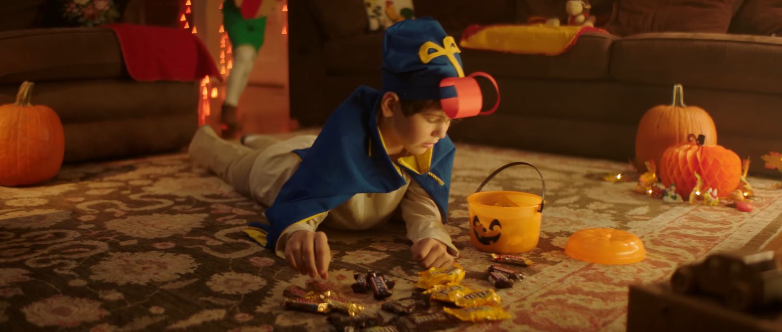 a little boy in a costume playing with some candy