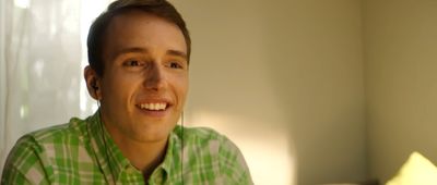 a man in a green and white shirt smiles at the camera