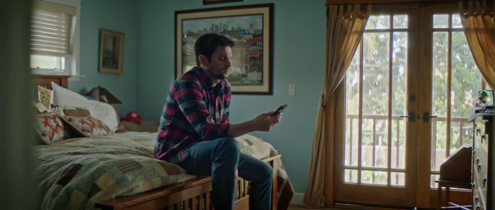 a man sitting on a bed holding a cell phone