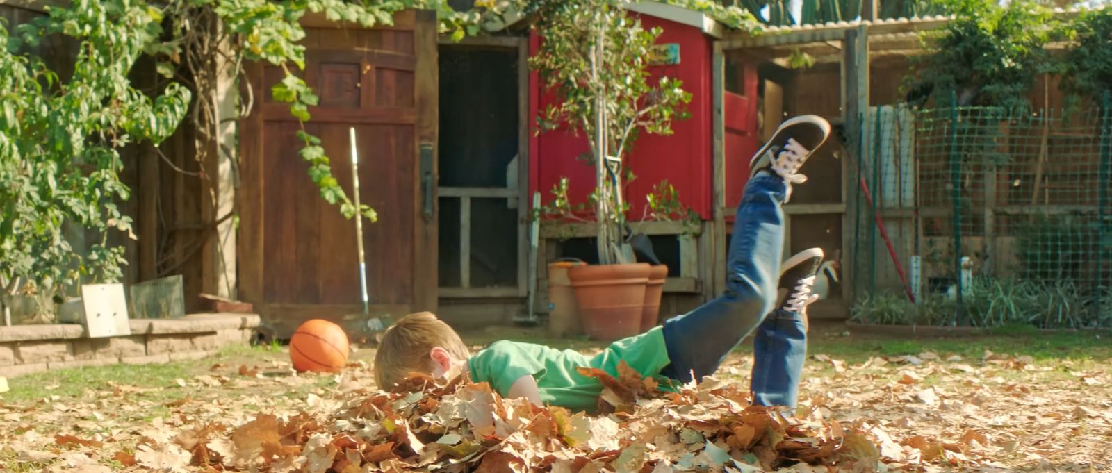 a young boy laying on top of a pile of leaves