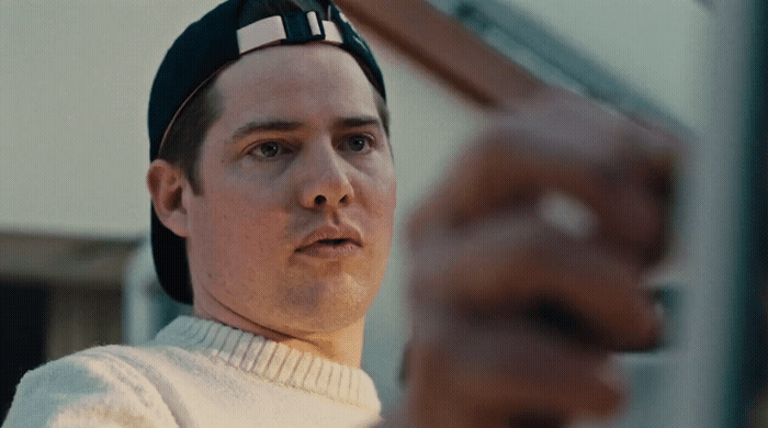 a man in a white sweater holding a pair of scissors