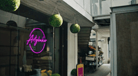 a store front with a neon sign hanging from it's side