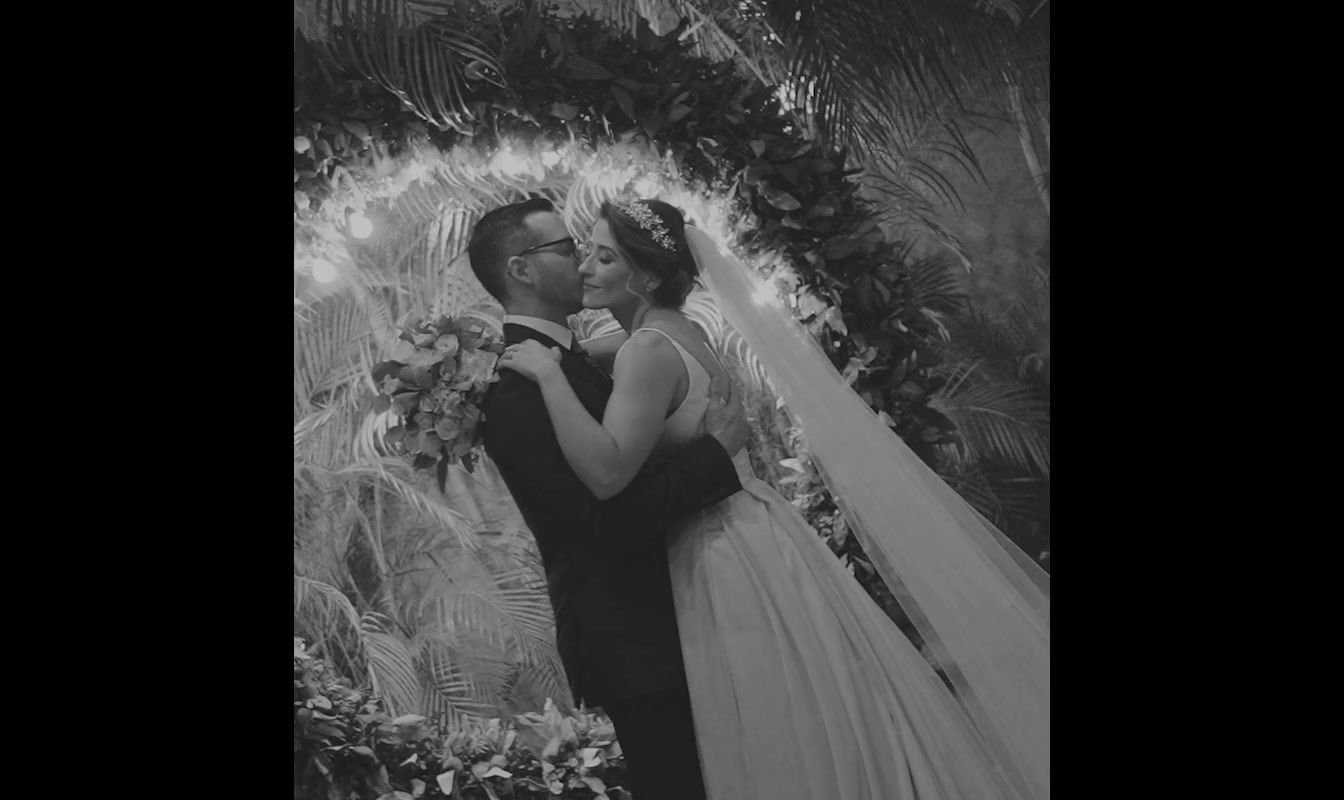 a bride and groom kissing in front of a floral arch