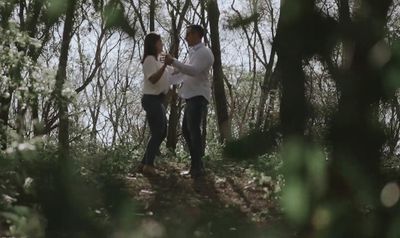 a man and a woman standing in the woods