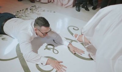 a man in a white suit and tie laying on the floor