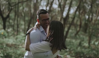 a man holding a woman in a forest