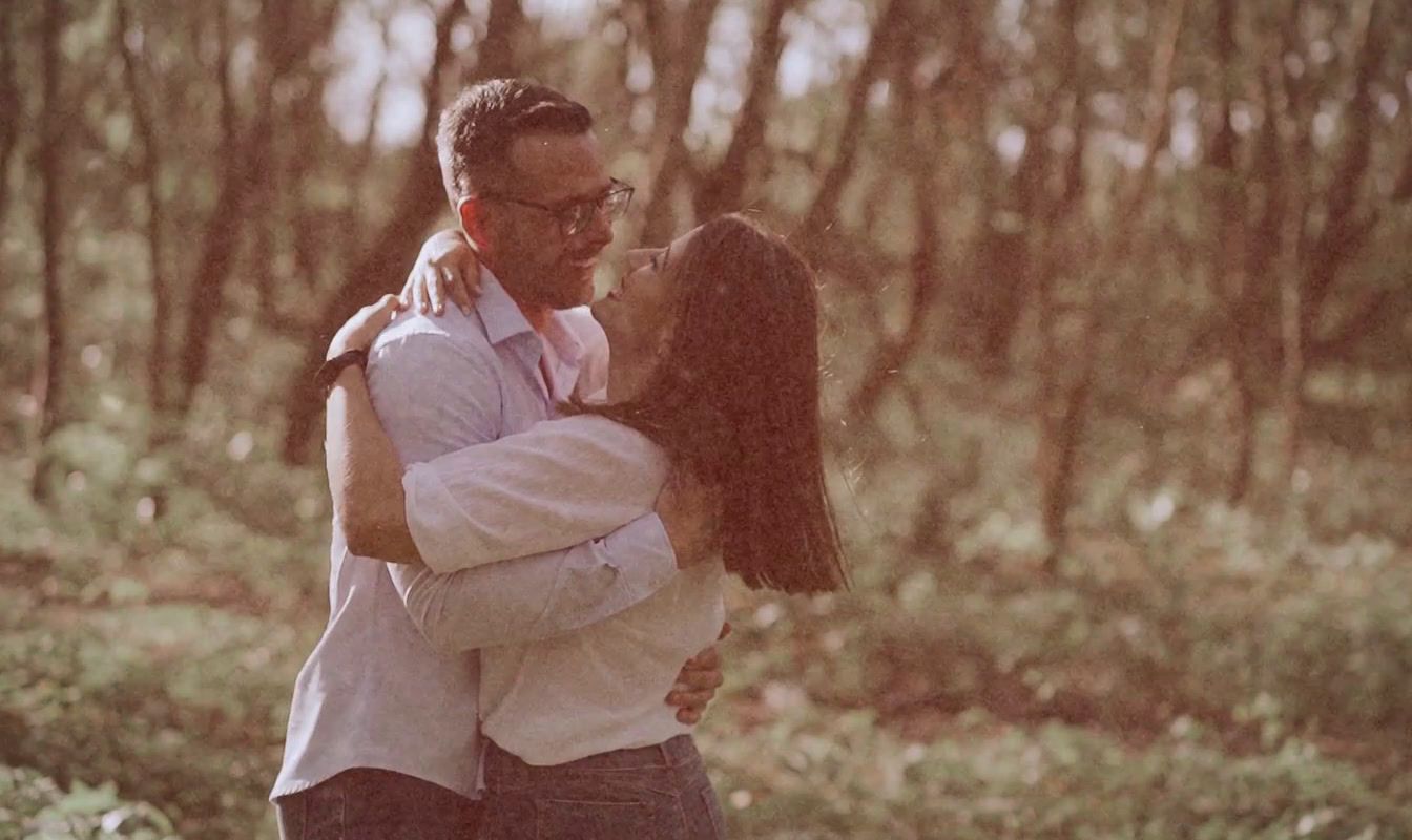 a man and a woman embracing in the woods