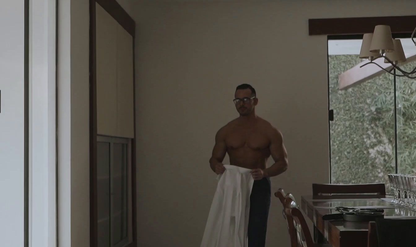 a shirtless man standing in a kitchen next to a table