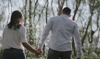 a man and a woman holding hands in the woods