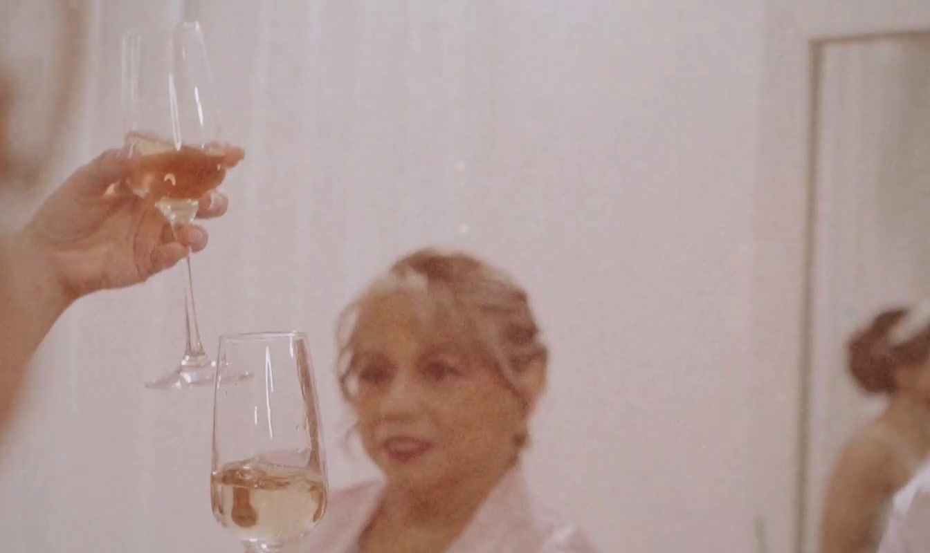 a woman holding a glass of wine in front of a mirror