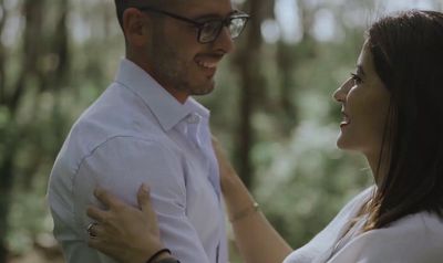 a man standing next to a woman in a forest