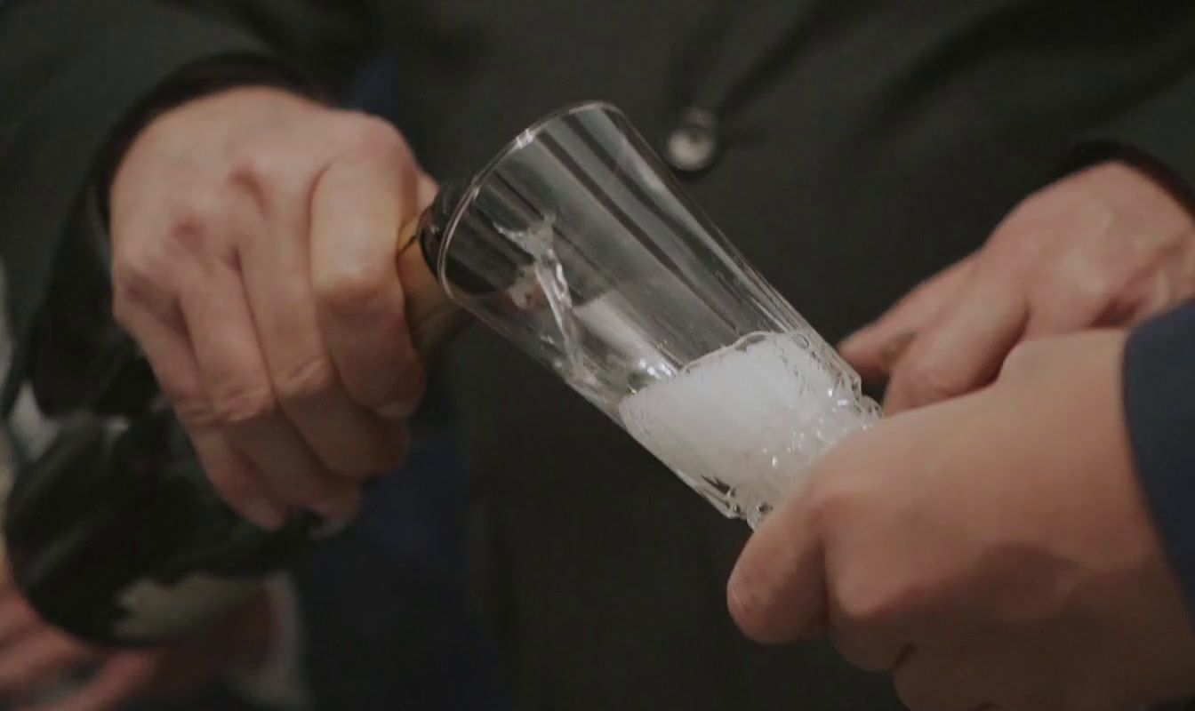 a person pouring a drink into a glass