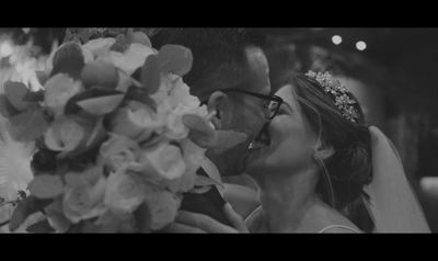 a bride and groom kissing in front of a bouquet of flowers