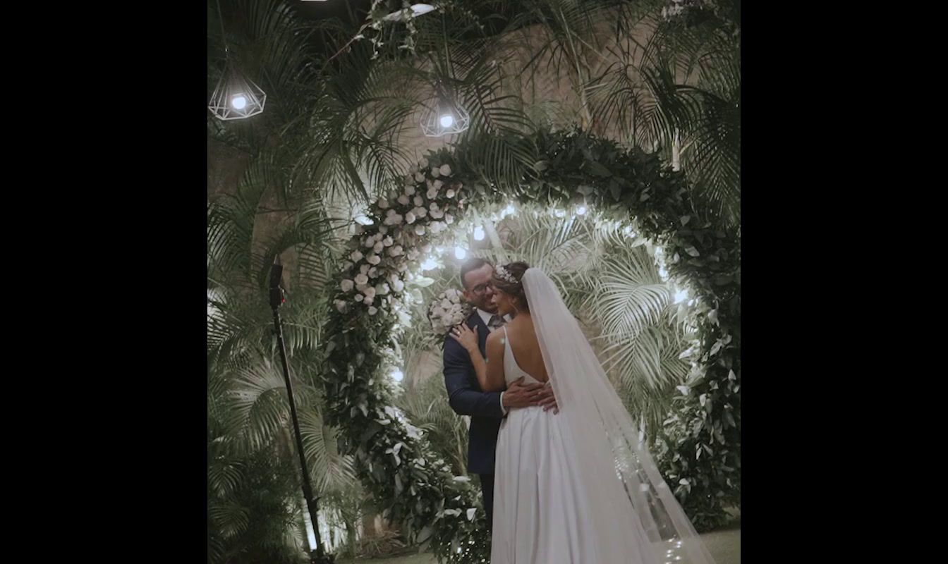 a bride and groom standing in front of a floral wall