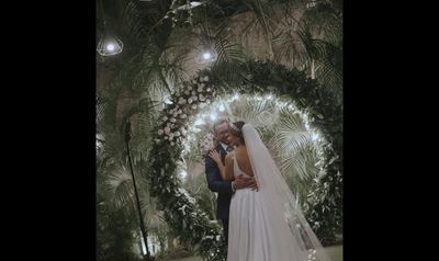 a bride and groom standing in front of a floral wall