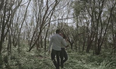 a man walking through a forest with trees in the background