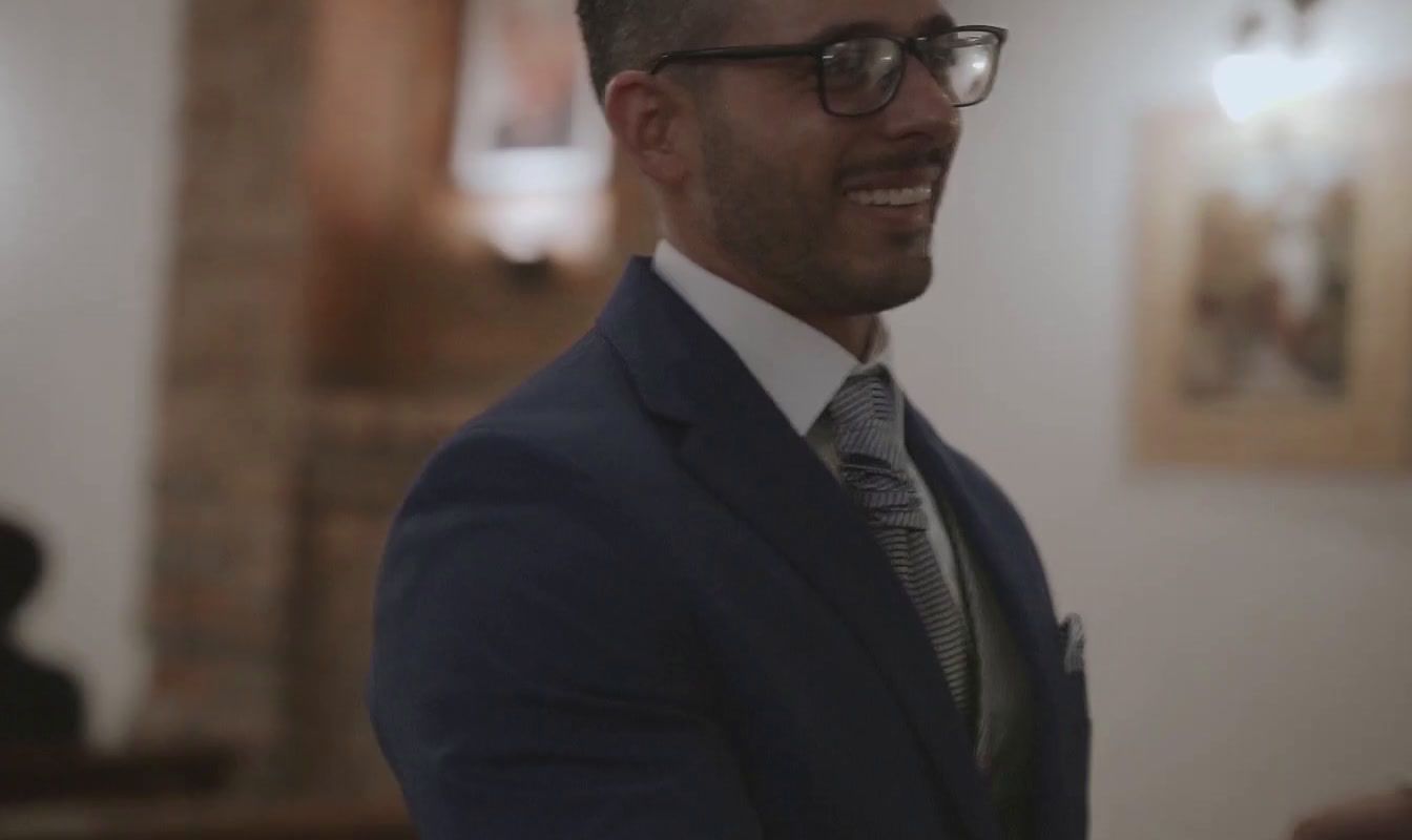 a man wearing glasses and a suit smiling