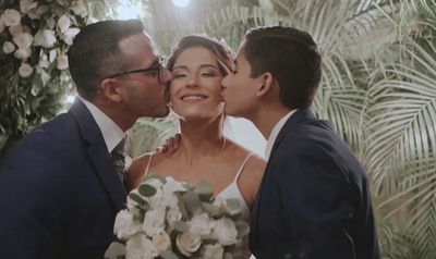 a bride and groom kissing in front of a palm tree