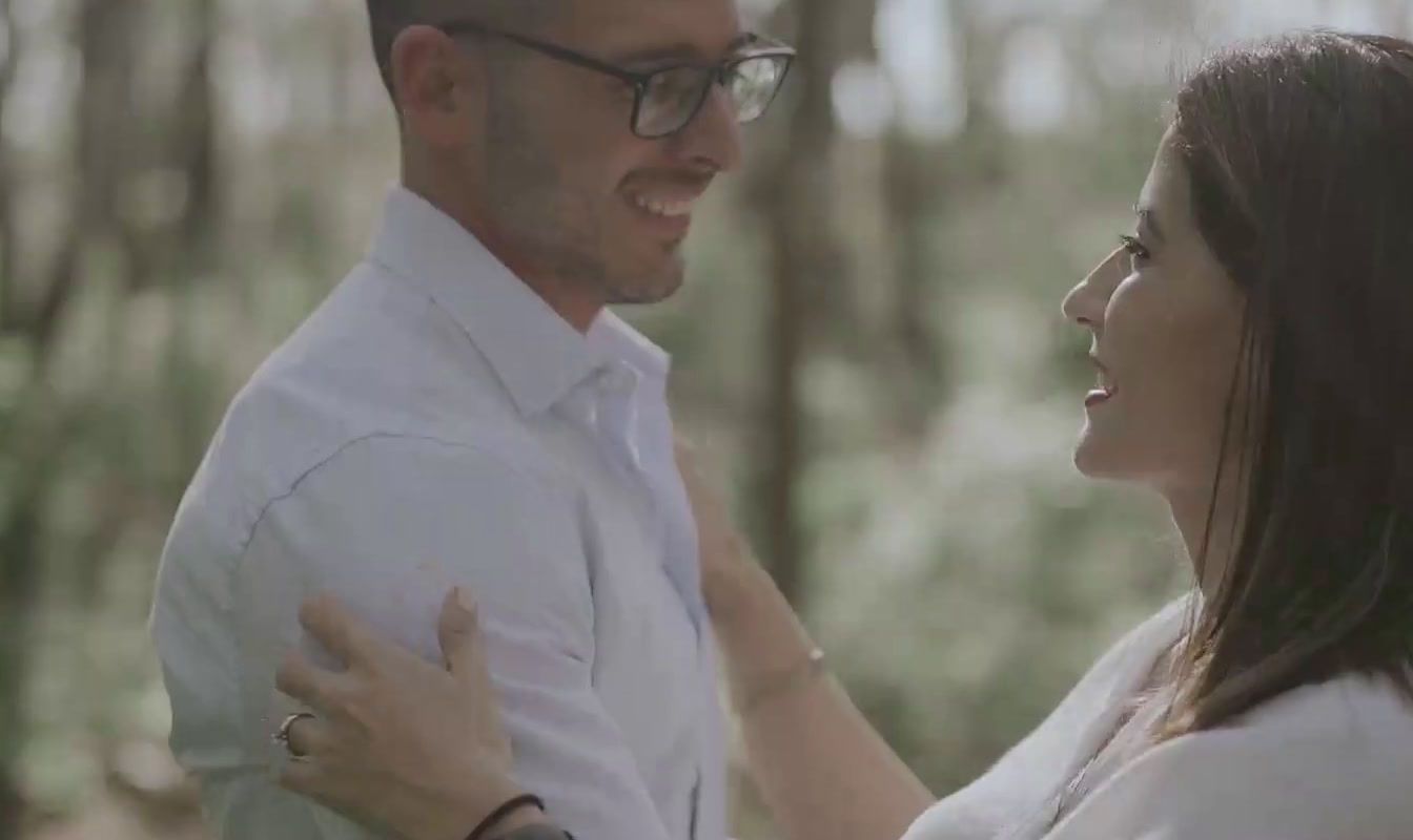 a man standing next to a woman in a forest