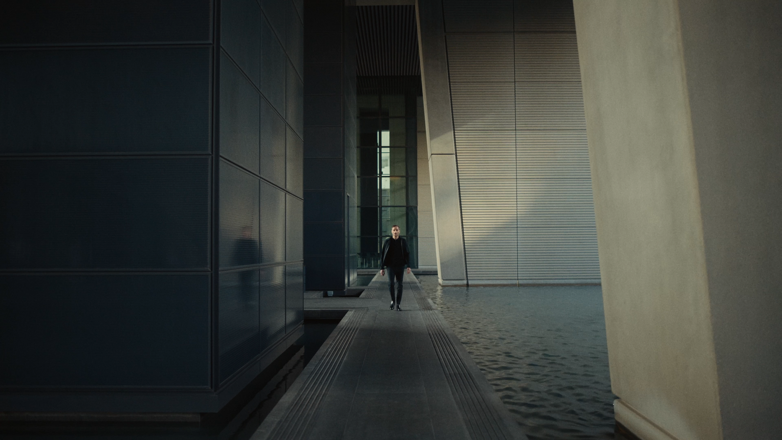 a man walking down a hallway between two buildings