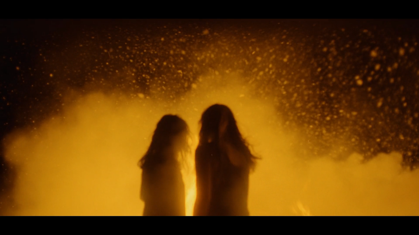 two women standing in front of a yellow smoke bomb