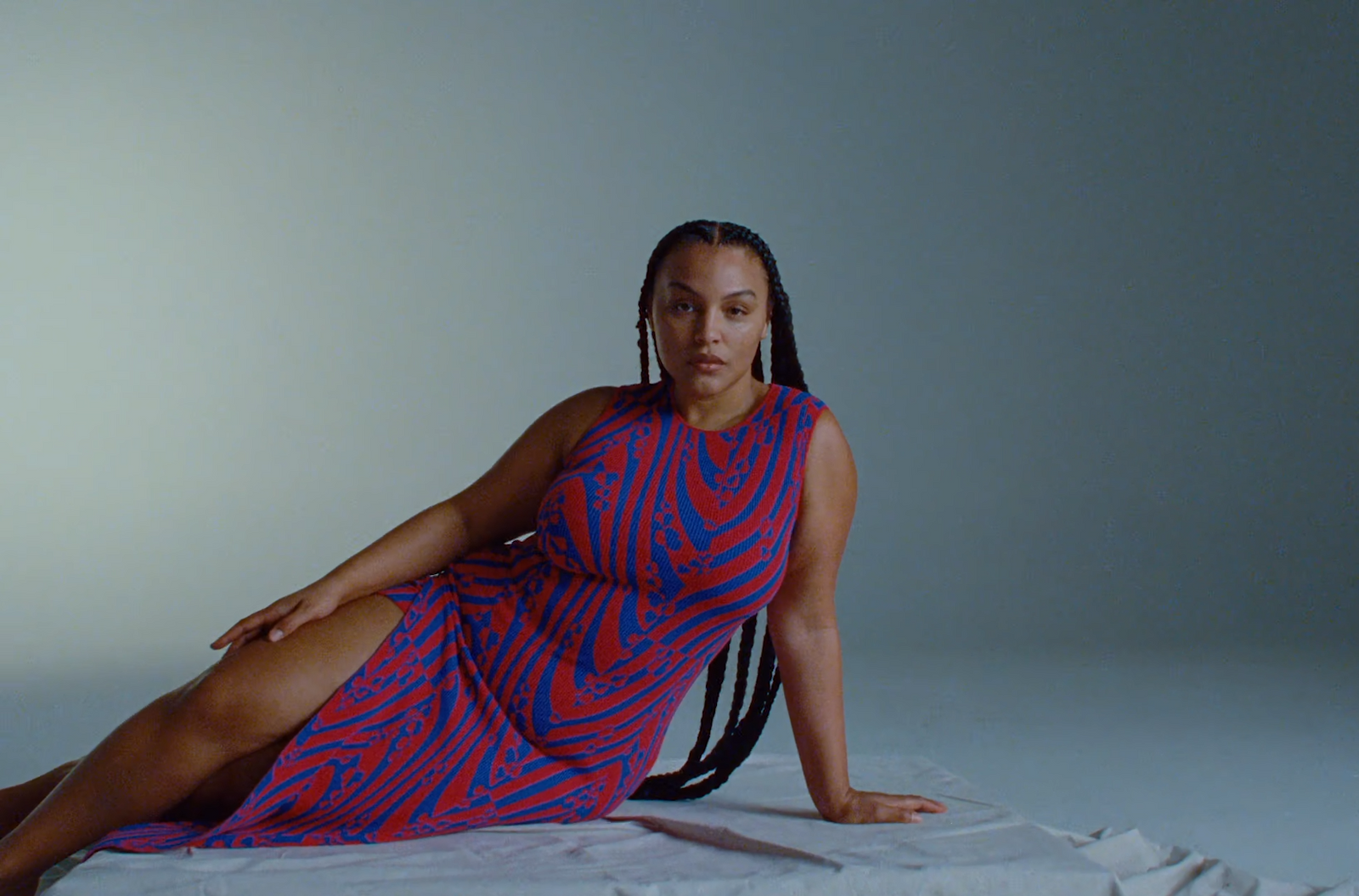 a woman in a red and blue dress sitting on a white sheet