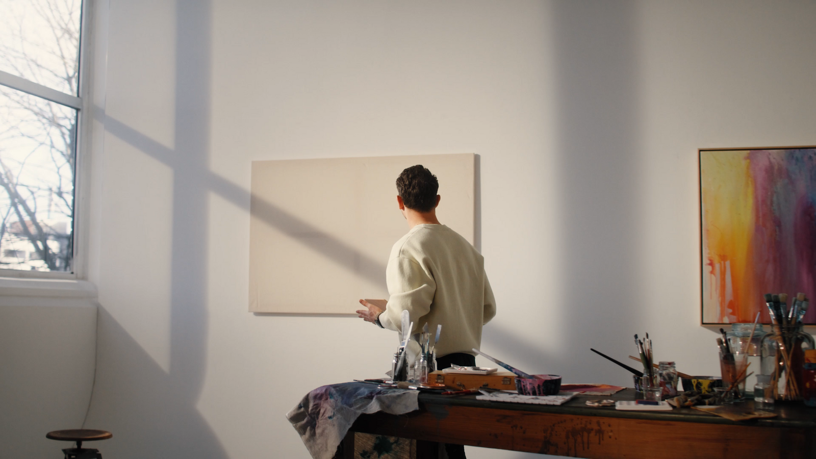 a woman standing in front of a painting on a table