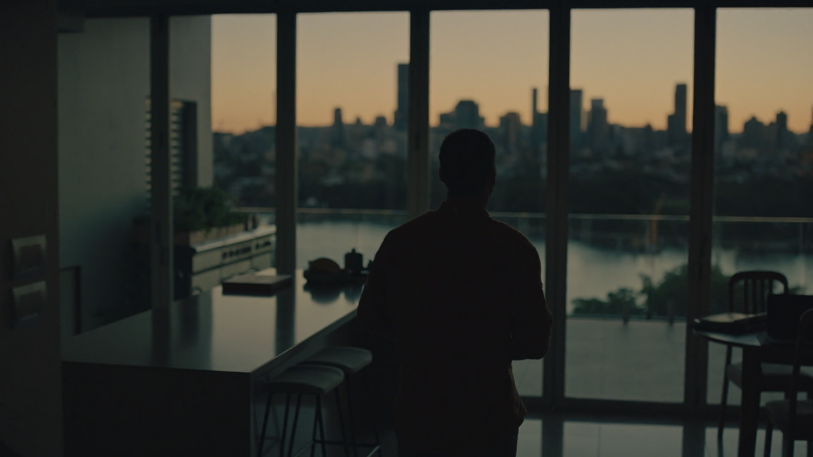 a man standing in front of a window looking out at a city