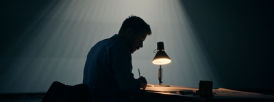 a man sitting in front of a desk with a lamp on it