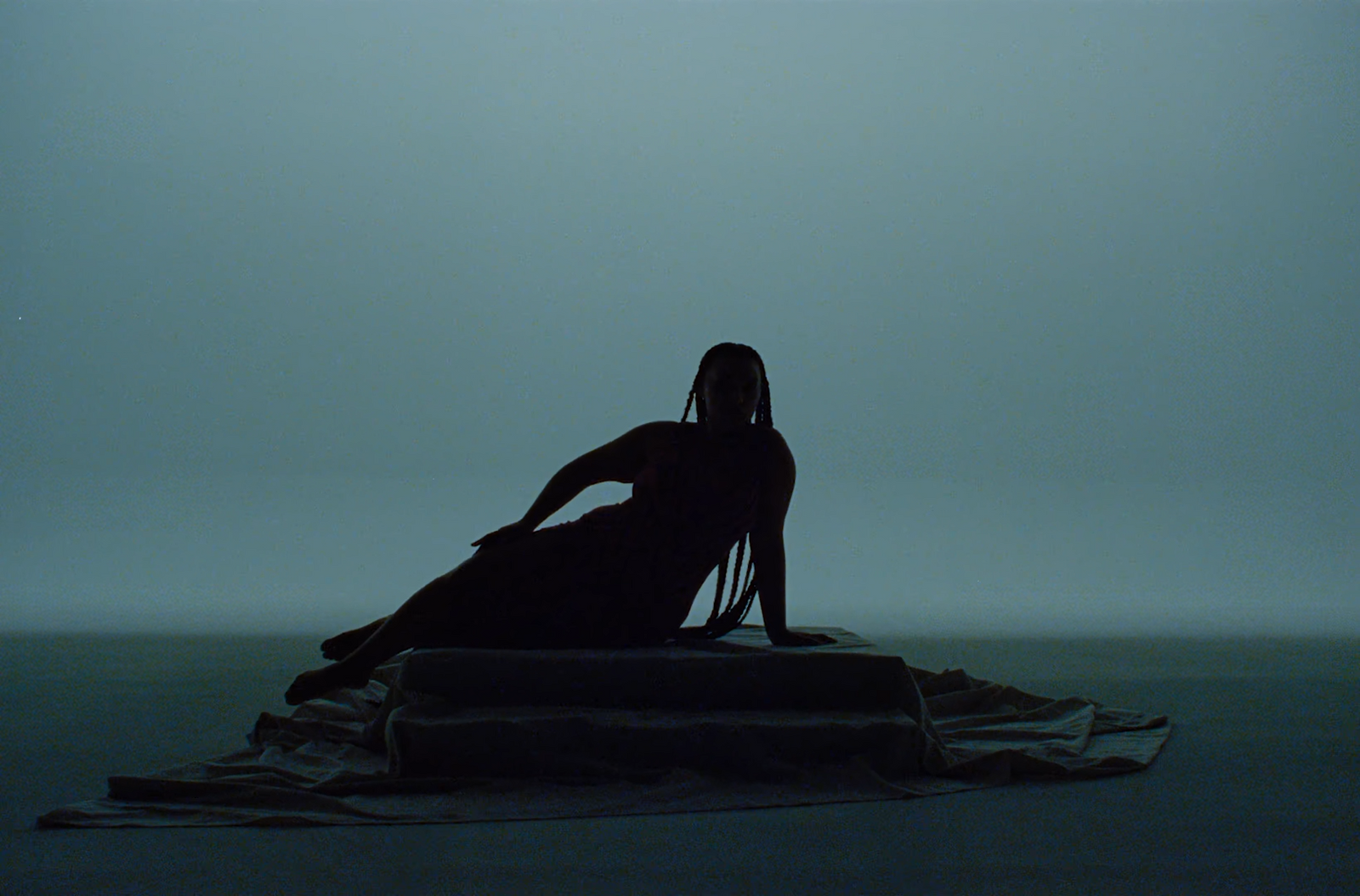 a silhouette of a woman sitting on a blanket