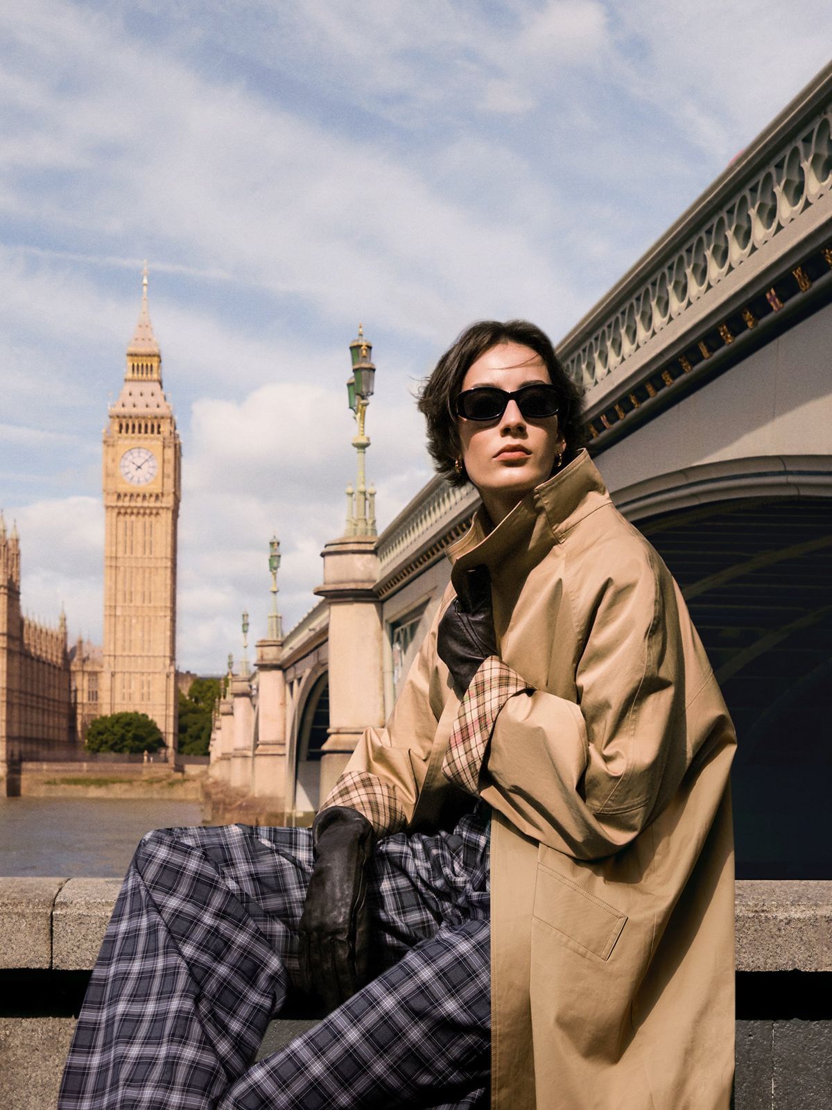 a man in a trench coat is sitting on a ledge