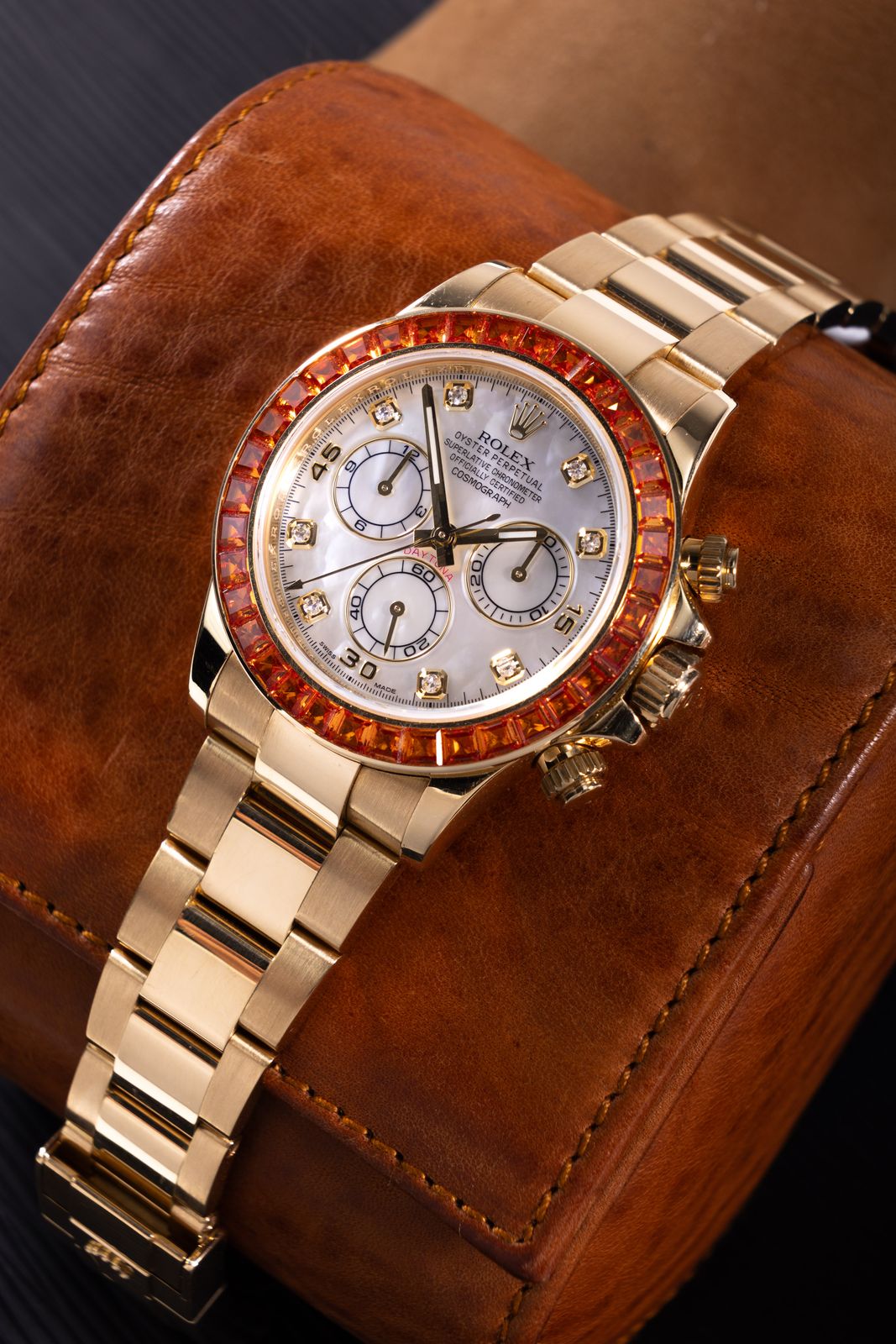 a gold rolex watch sitting on top of a brown case