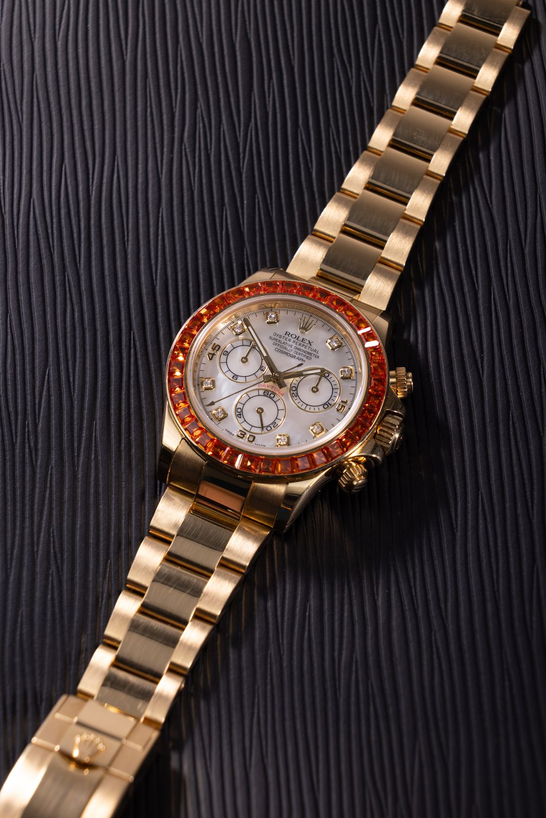 a gold watch on a black surface with a red diamond