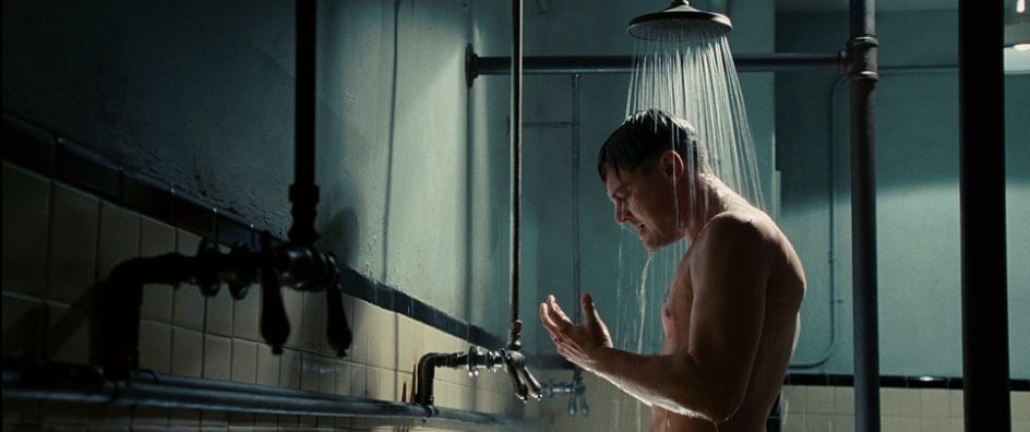 a shirtless man standing in a shower