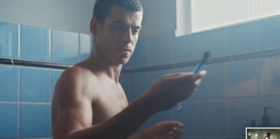 a shirtless man is brushing his teeth in the bathroom