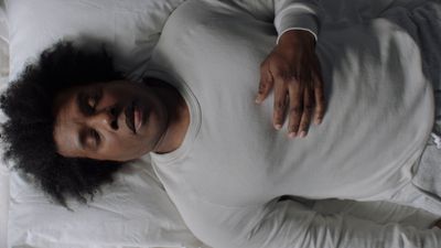 a woman laying on a bed with her hand on her stomach