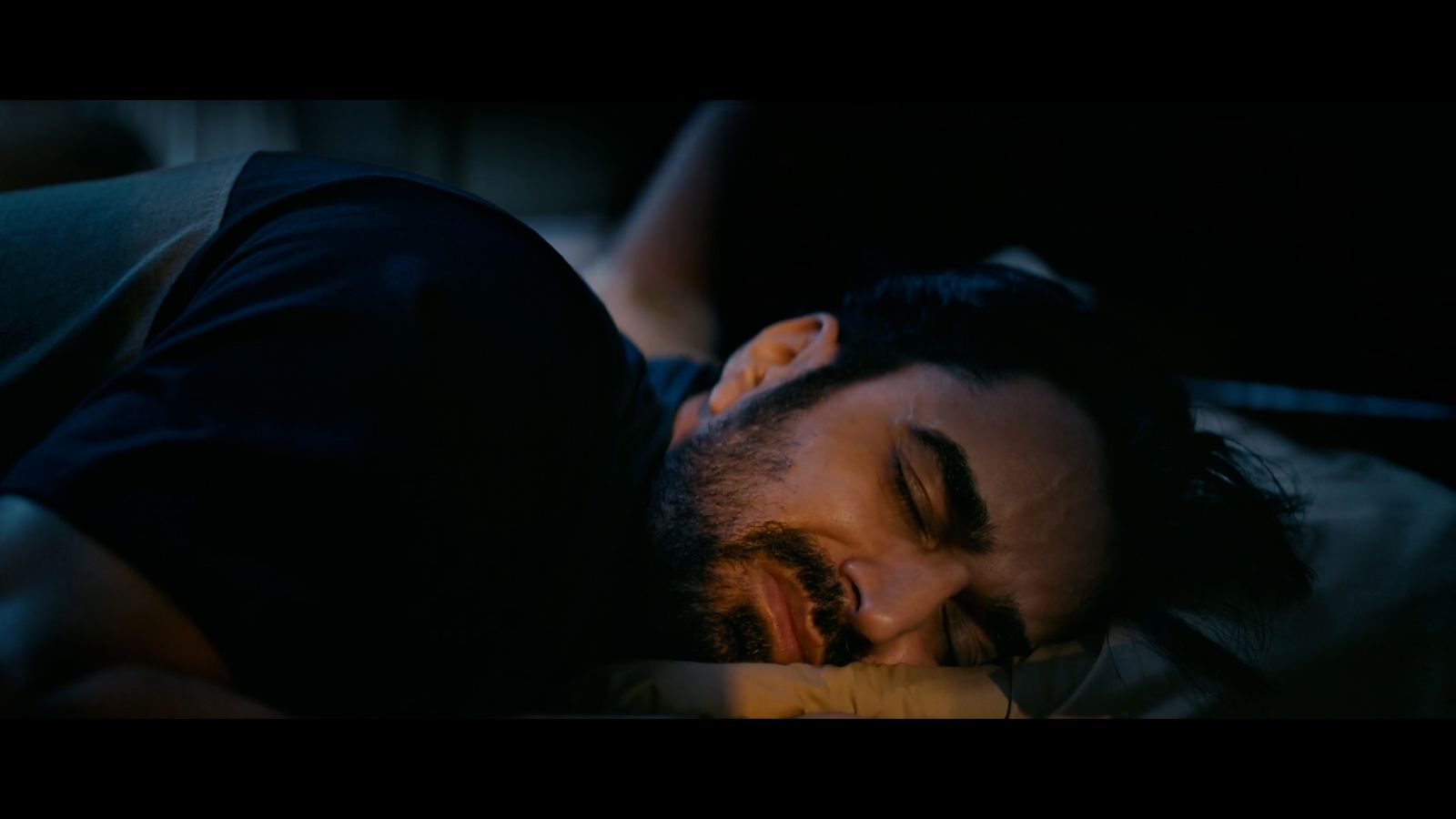 a man sleeping on a bed with his eyes closed