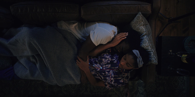 two people laying on a couch in the dark