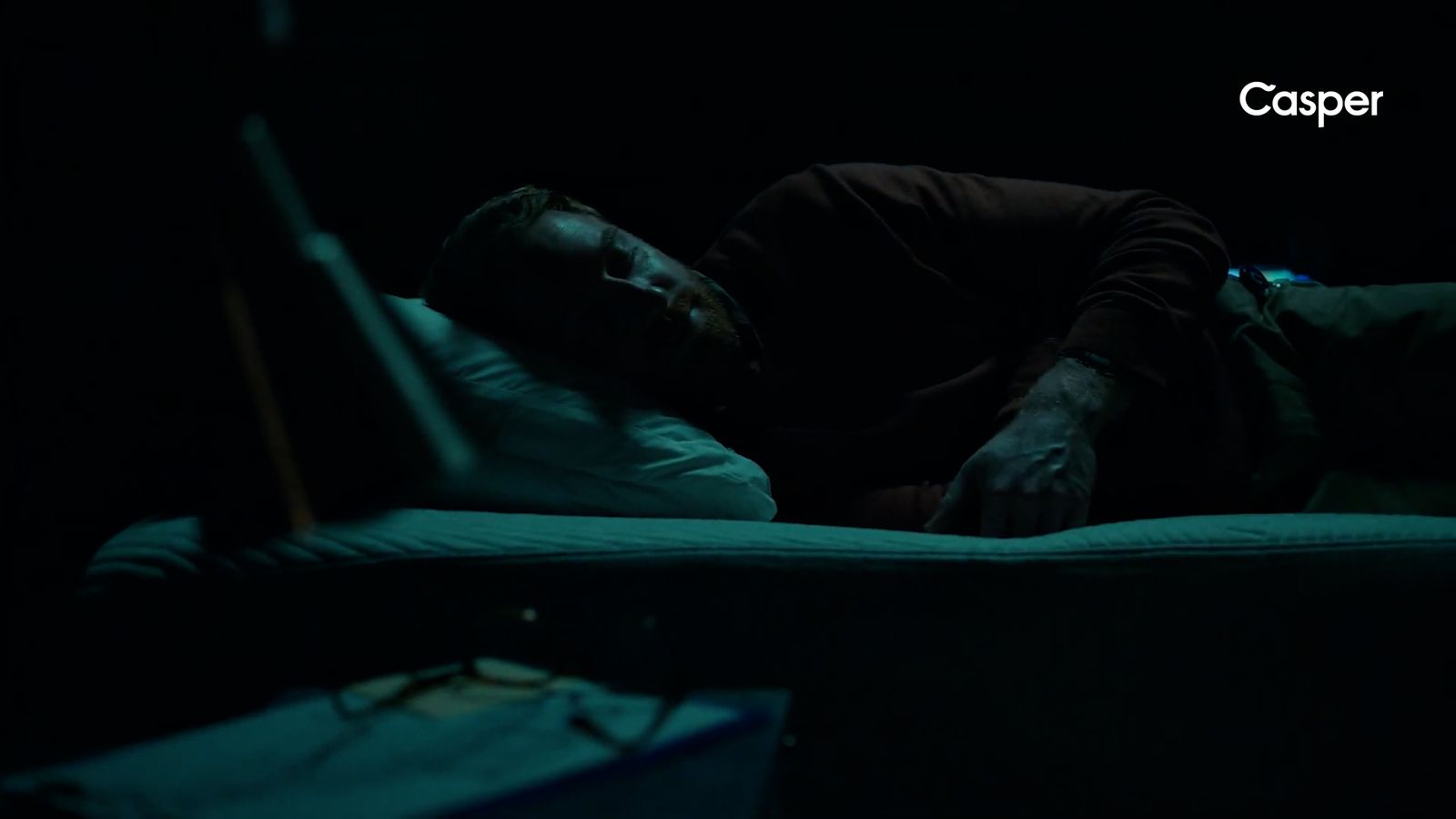 a man laying on a bed in the dark