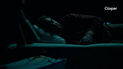 a man laying on a bed in the dark