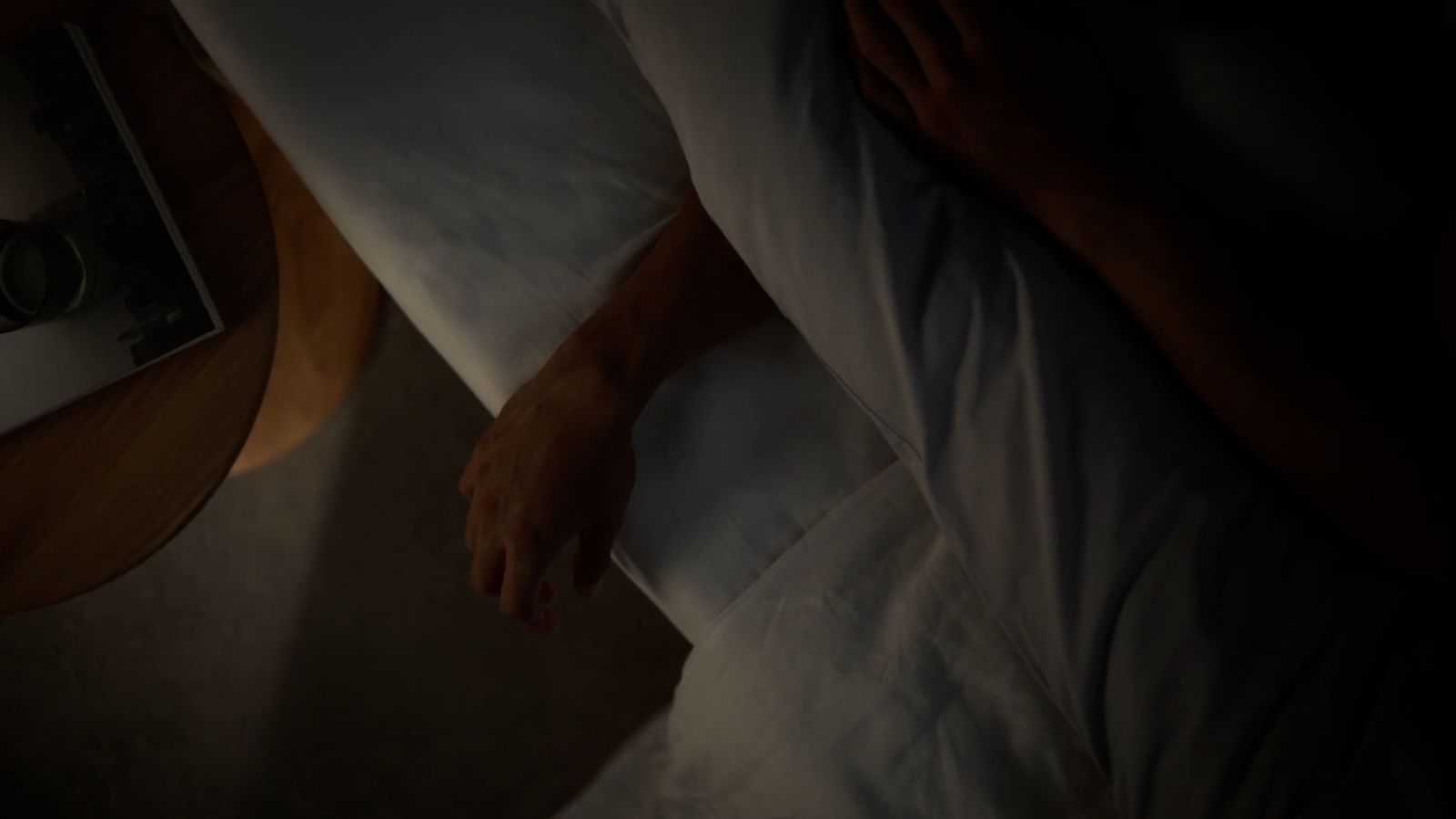 a person laying in a bed with white sheets