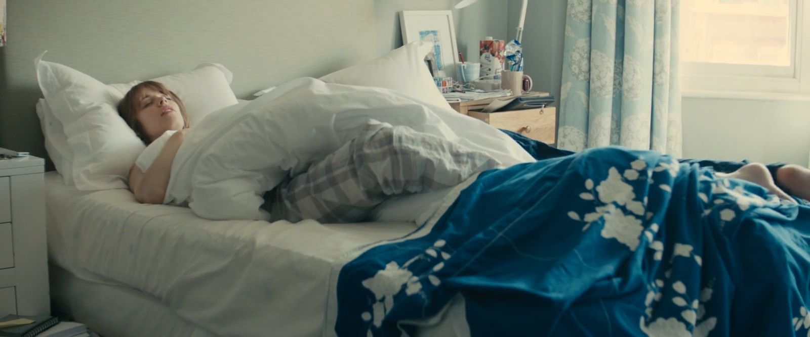 a woman laying in bed with her head on the pillow