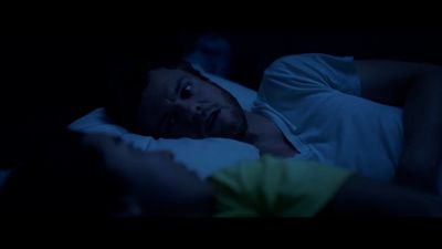 a man laying in bed in the dark