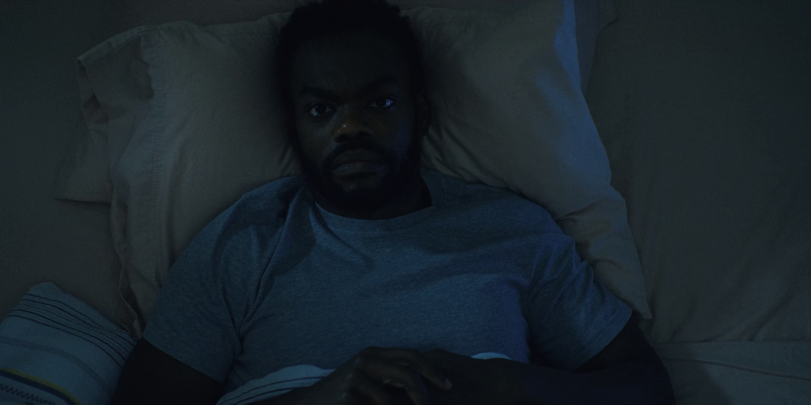 a man laying in bed in the dark