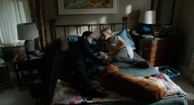 a man and woman laying on a bed next to a dog