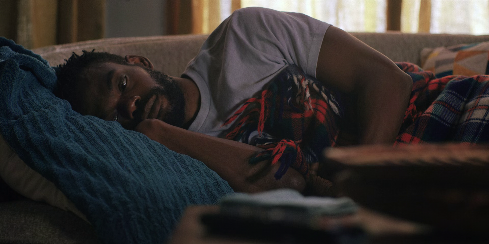 a man laying on top of a couch under a blanket