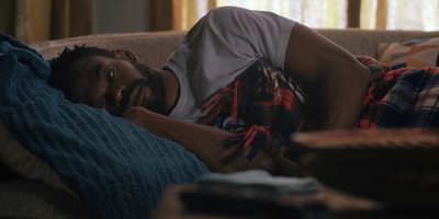 a man laying on top of a couch under a blanket