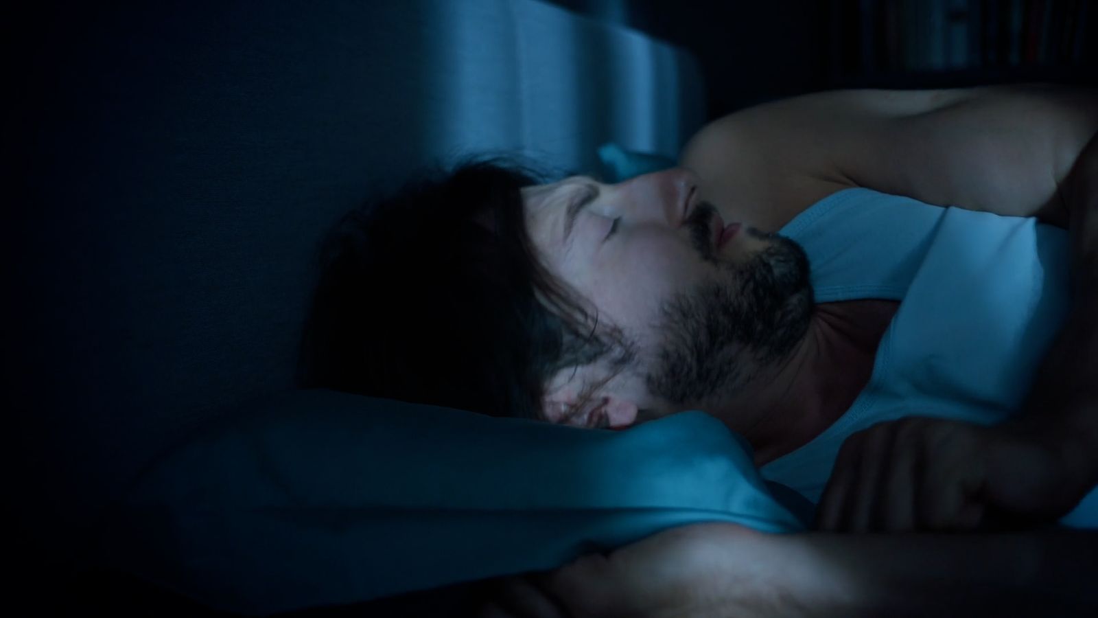 a man sleeping in bed at night with his eyes closed