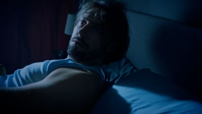 a man laying in bed in the dark