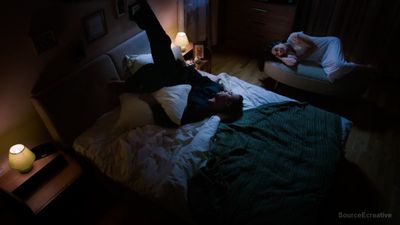 a man and a woman laying on a bed in a dark room